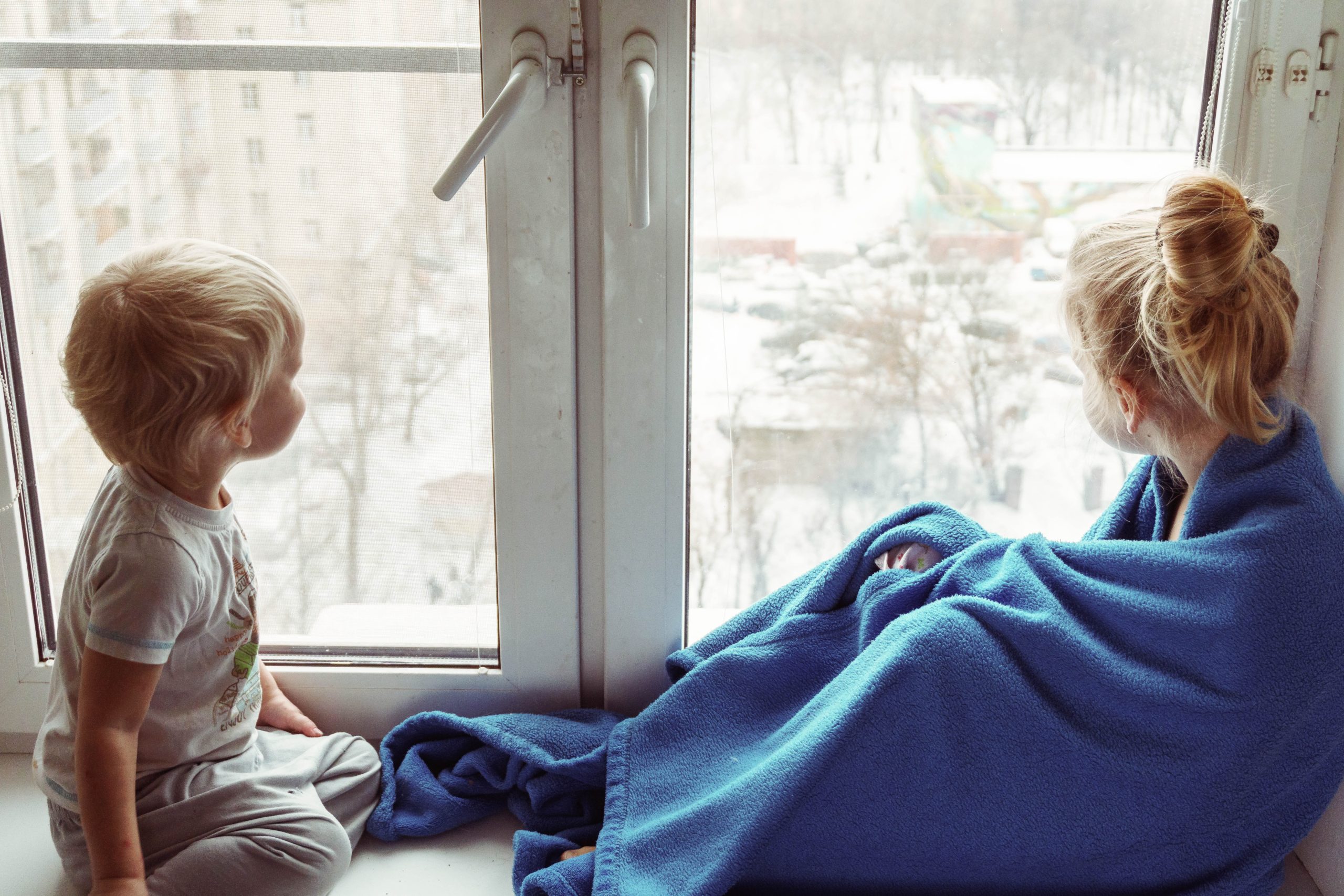 two kids looking out a casement window